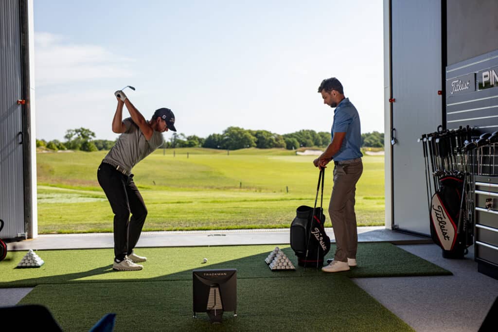 Ein Trainer unterstützt einen Golfspieler beim Abschlag mit einem Trackman Gerät